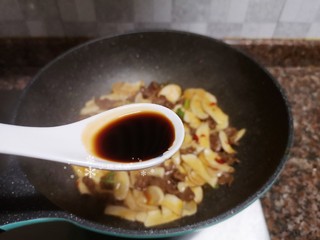 12、杏鲍菇炒牛肉,倒入适量生抽翻炒均匀。