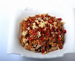 11、油淋腰花,把黄瓜拍破切小块和木耳放在大碗底部,上面放腰花,中间撒上刀口辣椒和剩下的蒜末。