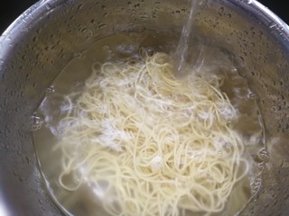 2、椒香葱油面,将面直接倒进漏篮，将热水全部滤出，动作要连贯迅速，不要拖拖拉拉，当然也要注意别烫着。面入盆用冷水冲，边冲边换掉里面的水。