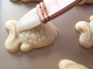 12、小鱼儿蔓越莓绿豆月饼,将月饼取出，待冷却一下，在表面刷上薄薄一层蛋黄水。继续烘烤15分钟