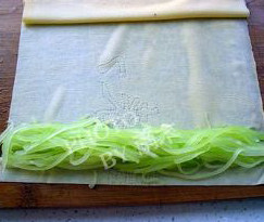4、莴苣两吃,取一张干豆腐平铺，放入焯水的莴苣丝，包卷起来