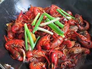 9、香辣小龙虾,然后加入葱段、一碗水盖上锅盖煮至汤汁浓稠