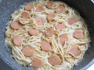 10、面条花式煎饼,面条倒入，将火腿肠片摆放在面条上面