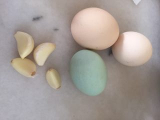 1、快手菜鲜香赛螃蟹（鸡蛋，咸蛋）,准备原材料，鸡蛋两个，咸鸭蛋一个，蒜若干