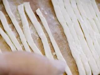 2、老北京炒疙瘩&海参过油肉,擀成面皮，折叠面皮，将面切成条状，铺平交叠