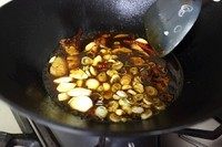 7、农家铁锅鱼,加入蒜瓣葱花翻炒几下后，再加入料酒、酱油、糖醋液烧开