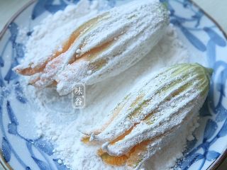 9、酥炸南瓜花,另外取一个碟子放入适量面粉，把南瓜花放在面粉上滚一圈；