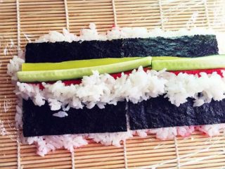 9、樱花寿司,掀开上面保鲜膜，将大根、黄瓜条、蟹肉棒排在上面，在一侧加上寿司米饭。