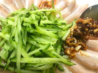 22、蒜泥白肉,把酱汁均匀的浇到五花肉和黄瓜丝上面