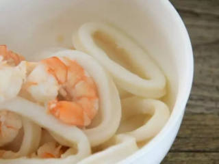 1、世界杯各国特色美食——西班牙海鲜烩饭,先将鱿鱼圈、虾仁，焯水捞出