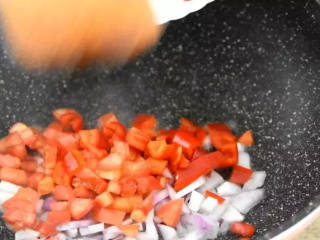 2、世界杯各国特色美食——西班牙海鲜烩饭,将洋葱、红椒、西红柿丁下锅，翻炒