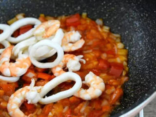 4、世界杯各国特色美食——西班牙海鲜烩饭,将焯熟的鱿鱼圈，虾仁，放入锅中
