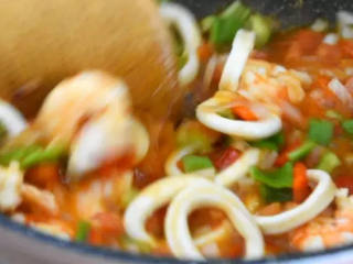 5、世界杯各国特色美食——西班牙海鲜烩饭,加入清水炒匀.煮开后，倒入青椒 ，翻炒均匀