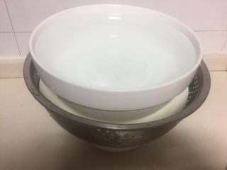 6、脆皮酱黄瓜,腌好的黄瓜装在沥水篮里,下面垫一个碗,上面放一个重的东西压实,把黄瓜里的水份全部挤出来。