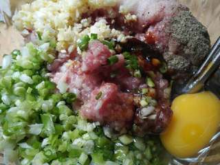 2、苏式萝卜干鲜肉月饼,放入切碎的葱姜蒜末,倒入料酒、生抽、耗油、花椒粉、胡椒粉、盐、白糖、芝麻油,打入一个鸡蛋顺时针方向一直搅动。