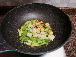 10、蒜苗炒猪肝,放入蒜苗头和大蒜、生姜、小米辣翻炒出香味。