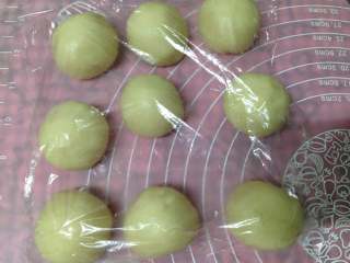 11、手捧着吃的――咖喱鸡肉月饼,将所有包好的面团收口向下盖上保鲜膜，静置松驰20分钟