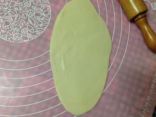 12、手捧着吃的――咖喱鸡肉月饼,取1个松驰好的面团用手按平，再用擀面杖擀成椭圆形