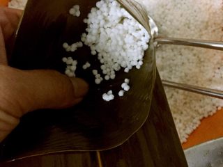5、紫薯水晶粽,将粽叶斜折成漏斗状,放入少许西米,用筷子压实。