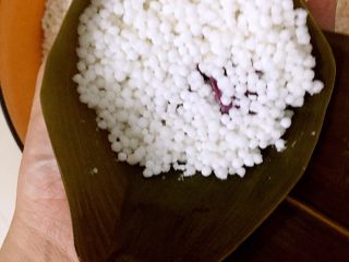 8、紫薯水晶粽,再放几粒紫薯丁,盖上西米,由于西米在煮后不会膨胀,所以在包的过程中一定要压实,以免煮熟后松散,不成形。