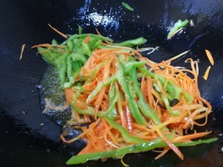 13、鱼香肉丝,锅里底油先放入胡萝卜丝煸炒均匀，再放尖椒丝文火炒匀。