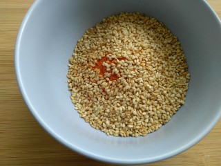 6、离不了的红油辣椒,芝麻炒熟后,倒入放有辣椒面的碗里。