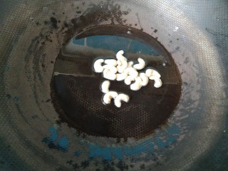 8、离不了的红油辣椒,倒入生腰果,不停翻炒,直到把腰果炸的金黄。