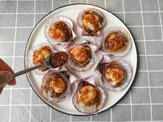 14、蒜蓉粉丝蒸扇贝,在扇贝肉上浇上制作好的汤汁。