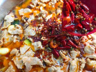 14、水煮肉片,在肉片上放上一勺辣椒粉,把花椒和干辣椒连油一起倒到辣椒粉上面,激出香味,放上葱叶和香菜即可开吃。