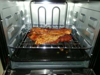 5、蜜汁叉烧,肉腌好3小时后、打开烤箱盖用筷子夹起肉停顿下再放在烤网上、碟上还残留点酱料还有用、用来涂在肉面上。