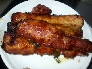 8、蜜汁叉烧,听到烤箱叮一声打开盖用夹子夹起烤好的肉装在碟上、看见表面还可以、边上有点烧焦、第一次使用还算满意。然后用刀子把它切成一片片摆上碟即可