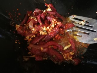 10、干煸牛肉,中小火慢慢炒，直到牛肉体力变小微干状态下倒入辣椒粉（这一步是为了做示范，实际上通常我是放自己的秘制红油里的油辣椒碎，味道更好）炒继续炒均匀。