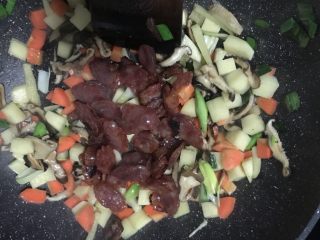 10、香菇腊肠焖饭,倒入腊肠继续炒2分钟