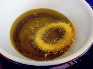 10、炸鱿鱼圈,放入油锅中，炸至浮起，翻面捞起