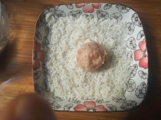 21、糯米丸子,把肉圆放入装有糯米的盘中。