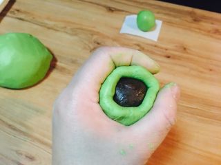 12、咸蛋黄肉松网红青团,慢慢收口，直到看不到馅。随后用两手掌心，不停的搓圆。