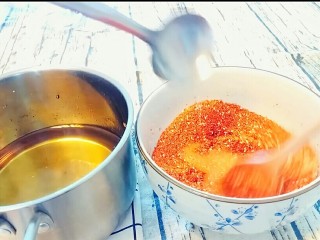 9、自制油辣子,先用小勺往辣椒面泼3勺油，趁热搅匀辣椒面。