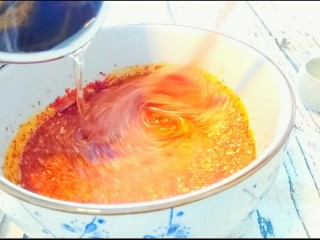 10、自制油辣子,端起小奶锅，将油慢慢倒进辣椒面，同时另一只手拿勺子搅拌辣椒面。直至油全部倒进去。