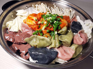 17、部队火锅,白菜上面码上金针菇，鸭血，水饺，中间放韩式泡菜，端上桌再加入鸡高汤，煮开即可
