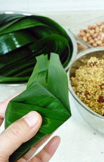 6、香浓里脊肉粽,再将多出的苇叶沿粽形折好，往左或者往右折都行，只要不漏米。