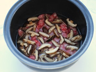 5、电饭煲腊肠煲仔饭,将大米淘洗干净后加入泡香菇的水，再加清水到正常煮饭的水量，将腊肠和香菇铺到上面，按煮饭键开始煮饭