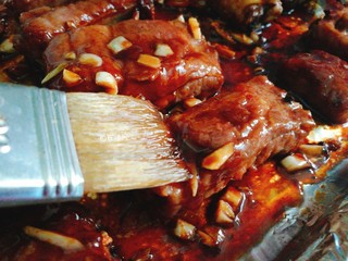 12、让人难抵诱惑的叉烧排骨,取出烤盘 猪肋排翻个面 在表面刷一层蜂蜜 再入烤箱 10分钟左右