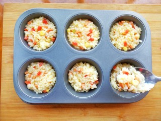 10、鸡蛋火腿米饭杯~,用勺子把调好的米饭装入模具里，并压实，七八分满即可，