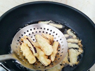 8、避风塘茄子,油锅烧热，放入裹满面糊的茄条，炸成微黄色，捞出控油。