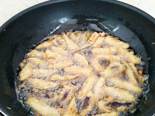 9、避风塘茄子,油锅再次烧热，烧到8成热，全部放入茄条，快去翻面，炸大约8秒钟左右。