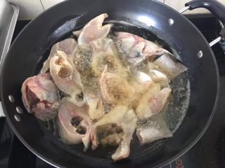 3、香辣入味的焖烧鱼块,炒锅放足量的油烧热，下入鱼块小火炸至金黄。