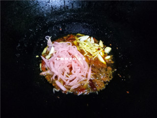 7、红烧鱼,放入酸萝卜丝、老姜丝、大蒜，继续翻炒；