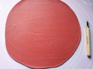 6、五福灯笼,将发酵好的面团分别排气揉匀后，取一红色面团擀成1cm厚的面片，然后用美工刀刻画出一个高18cm、宽（直径）20cm的灯笼形状。