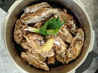 3、酱汁牡蛎,高压锅加一点点清水（水位约2厘米左右） 丢一片姜进去 然后把处理干净的牡蛎码好 上面放一片姜跟小葱盖上盖子。