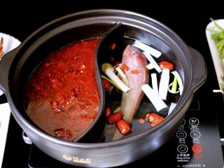 16、海鲜麻辣鸳鸯火锅,把炒好的调料倒入鸳鸯锅中加入适量清水、另一边清汤里加入适量清水